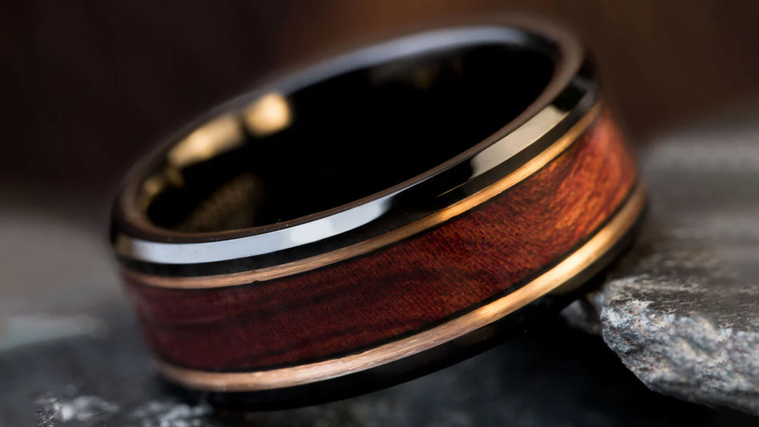 A stylish ring featuring a dark reddish-brown wood inlay, framed by thin metallic accents, and set within a high-gloss black band