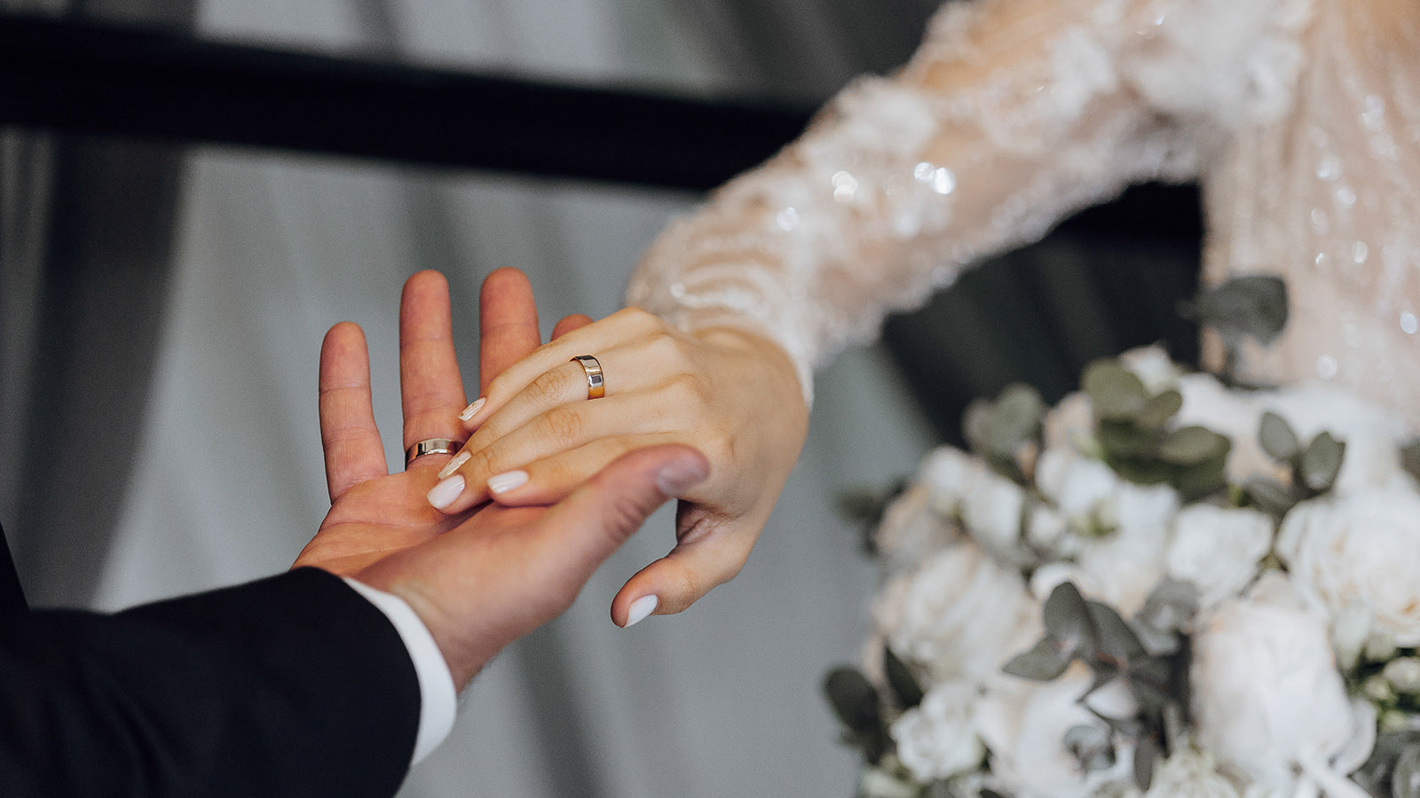 Bride and groom exchanging wedding rings during ceremony with bouquet in background