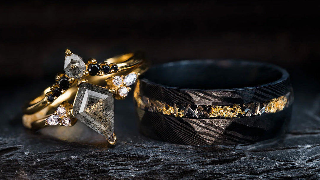 A bold sagaband duo featuring a gold-set galaxy ring and a wide, textured black band with gold flecks