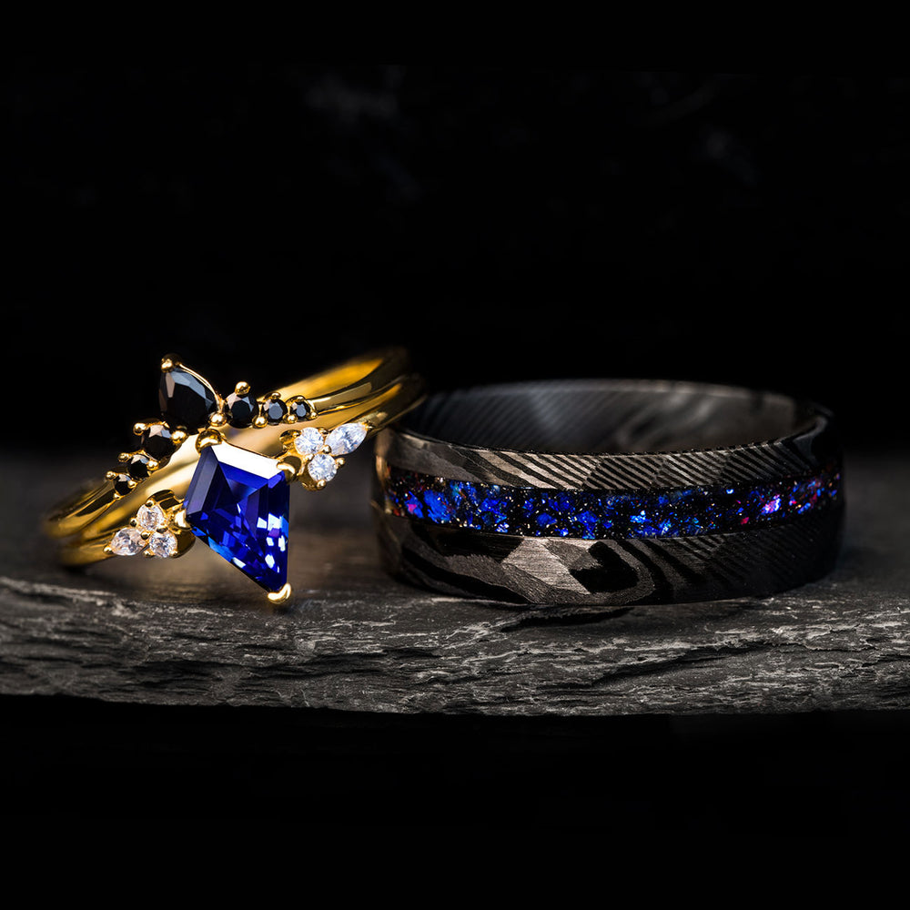 The Dark Moon ring set: gold band w/ kite-cut blue gem, diamonds, black stones & black Damascus steel band w/ blue inlay.