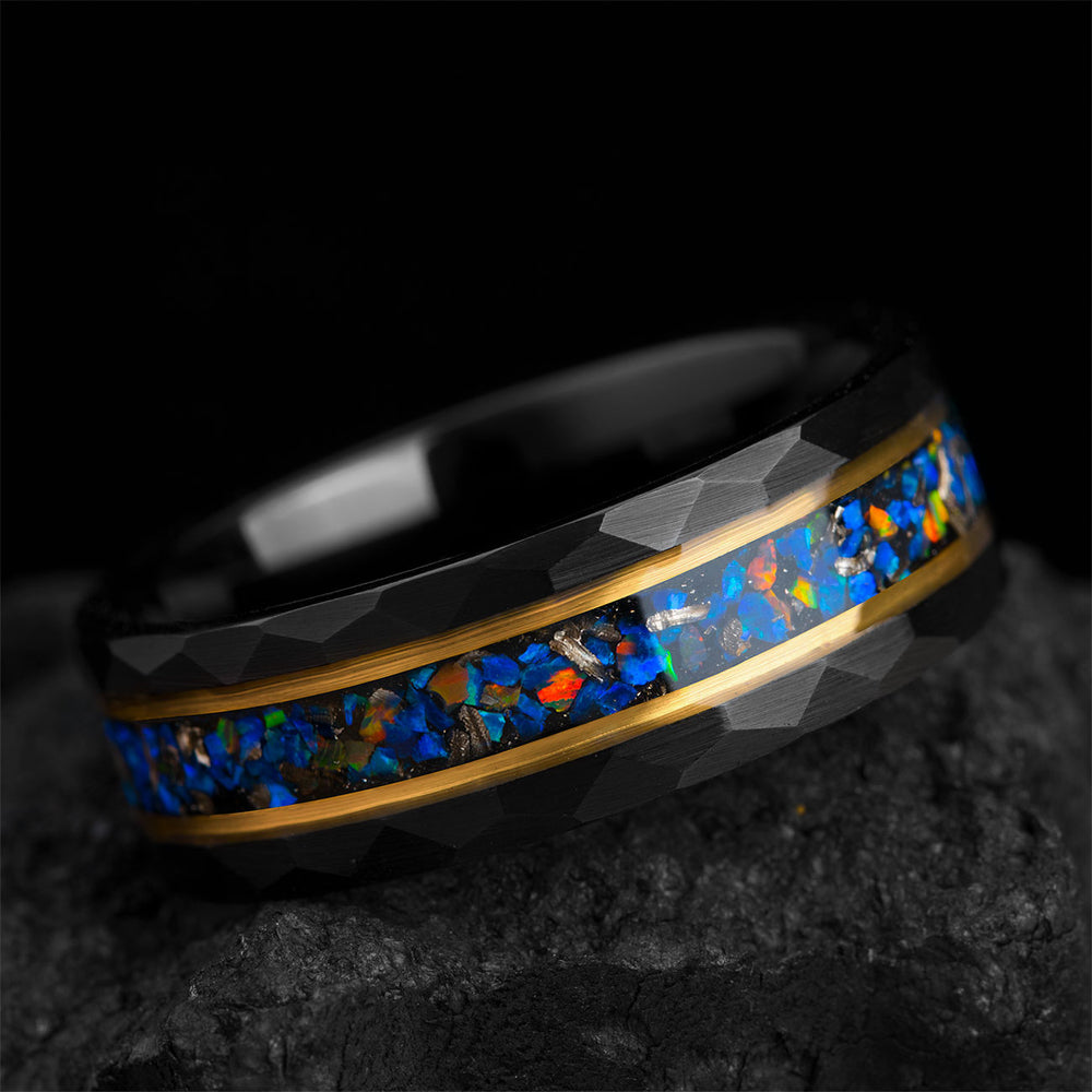 Hammered black tungsten ring with blue-orange opal inlay, meteorite pieces, and gold accents. Product detail shot.