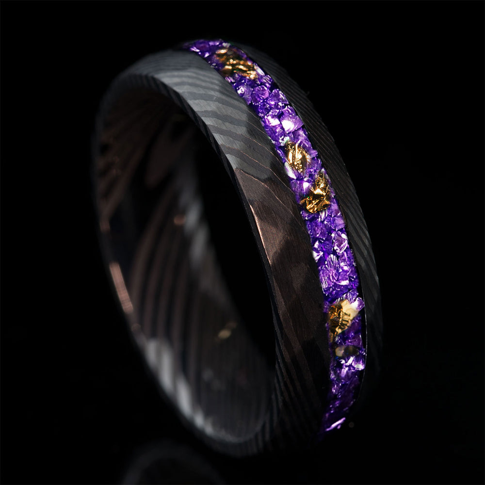 THE STORM FLAME wedding ring: black hammered Damascus steel with violet German glass and 22k gold leaf inlay on product page.