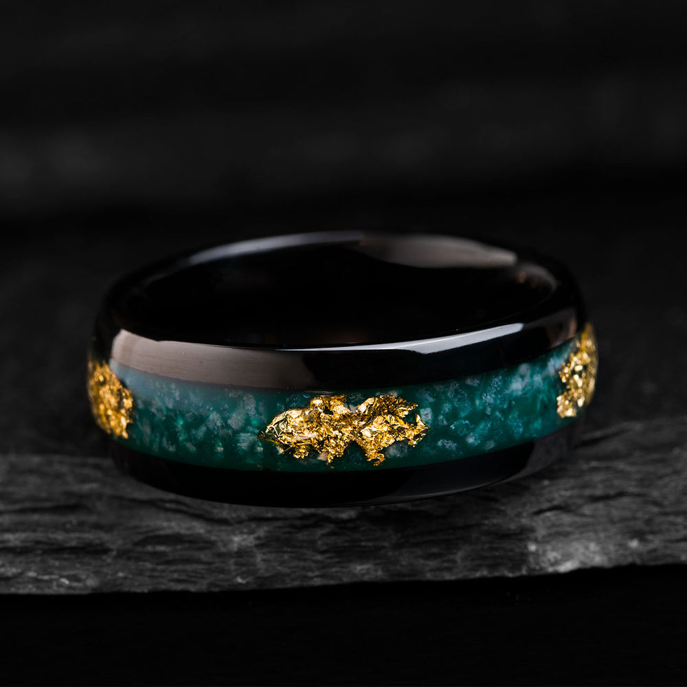 Black tungsten ring with vibrant green agate inlay and 22k gold leaf accents, showcasing material details and design.