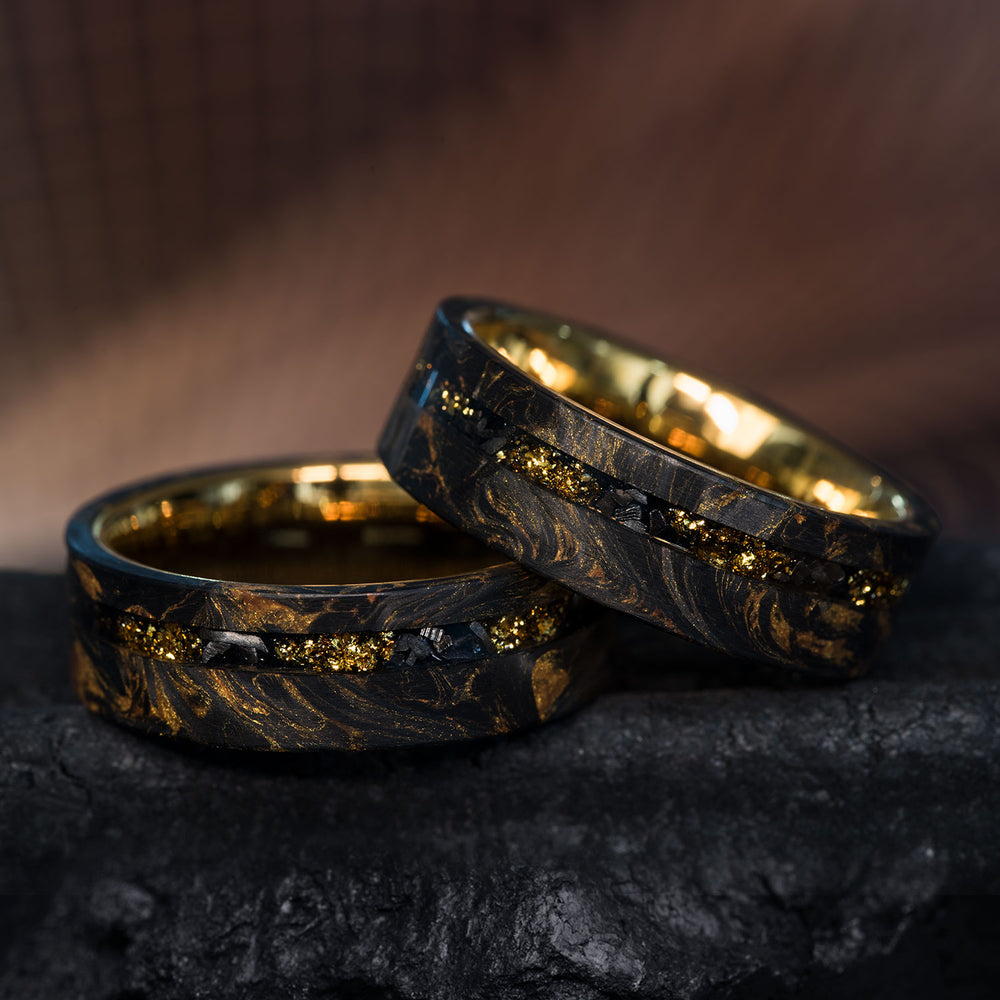 Two Sun God men's wedding rings: black forged carbon fiber, gold foil, meteorite inlay, polished gold tungsten interior.