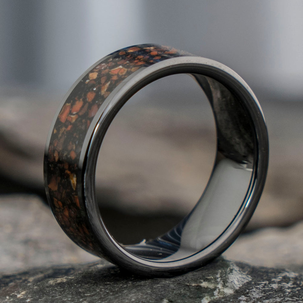 Black tungsten ring featuring a unique, matte T. Rex fossil bone inlay with earthy tones. Product showcase.