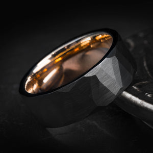 Black hammered tungsten wedding band with rose gold interior