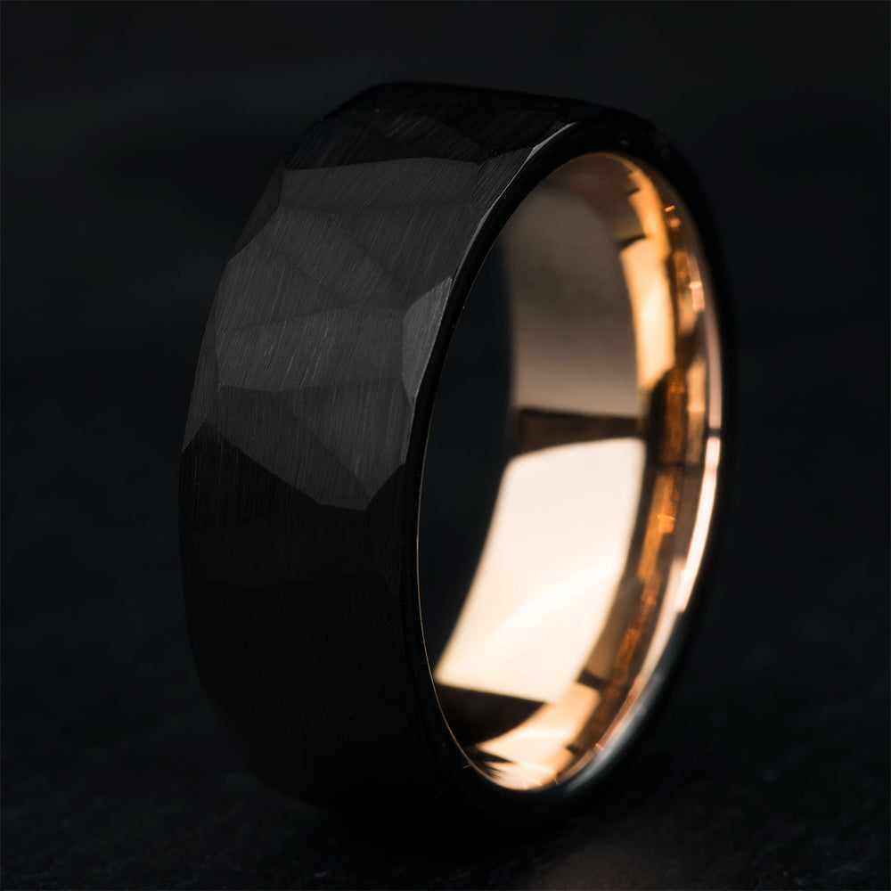 Black hammered tungsten carbide men's wedding band, faceted exterior, product shot.