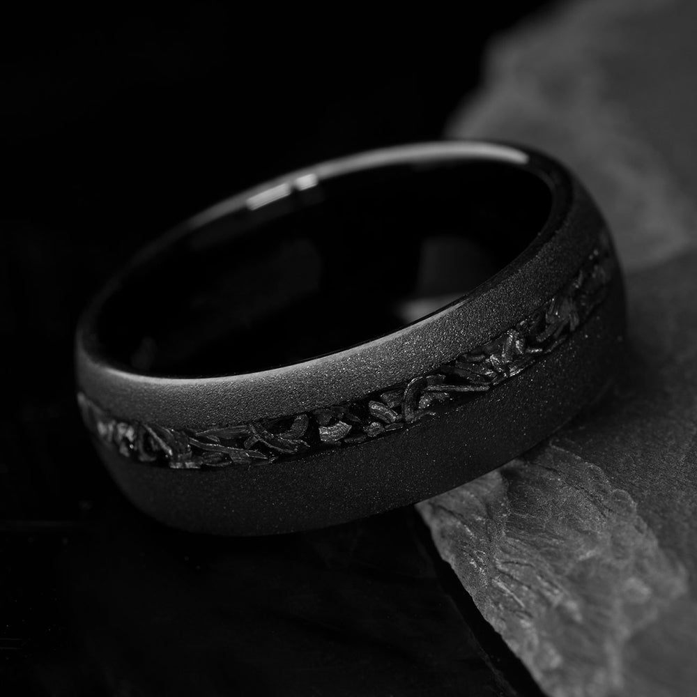 Matte black tungsten ring with sandblasted finish and Gibeon meteorite inlay, showcasing unique cosmic patterns.