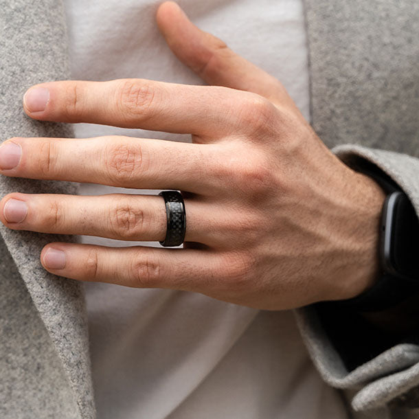 Man's hand wearing black carbon fiber ring, close-up