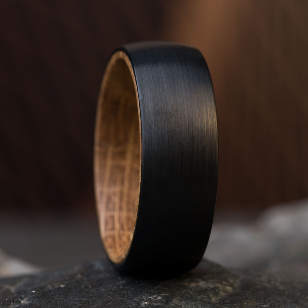 Close-up of The Dark Knight wedding ring, black tungsten with whiskey barrel wood inlay.