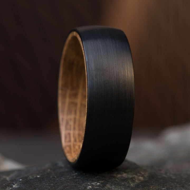 Close-up of The Dark Knight wedding ring, black tungsten with whiskey barrel wood inlay.