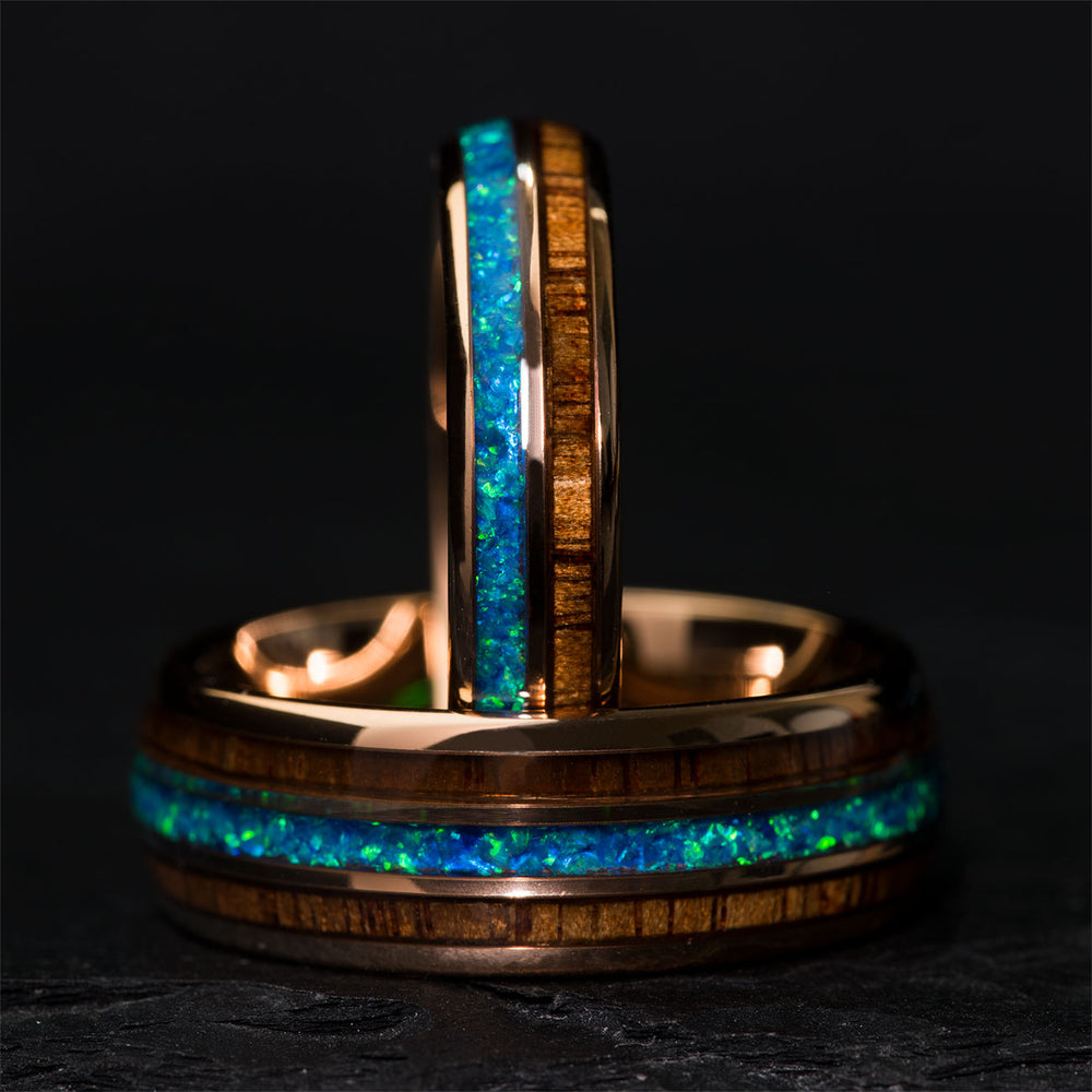 Rose gold tungsten ring with blue opal and koa wood inlay, showcasing inlaid detail.