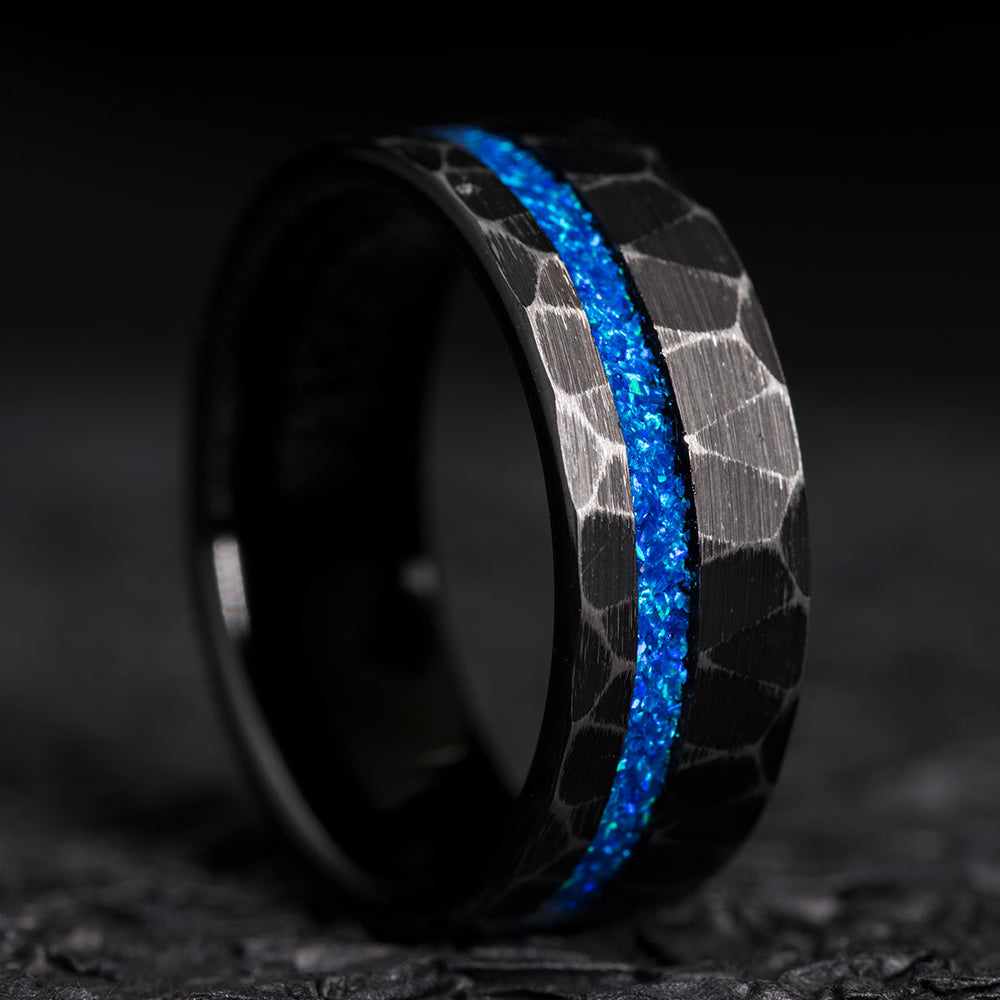 THE THOR men's black hammered tungsten wedding band with vibrant blue opal pinstripe.
