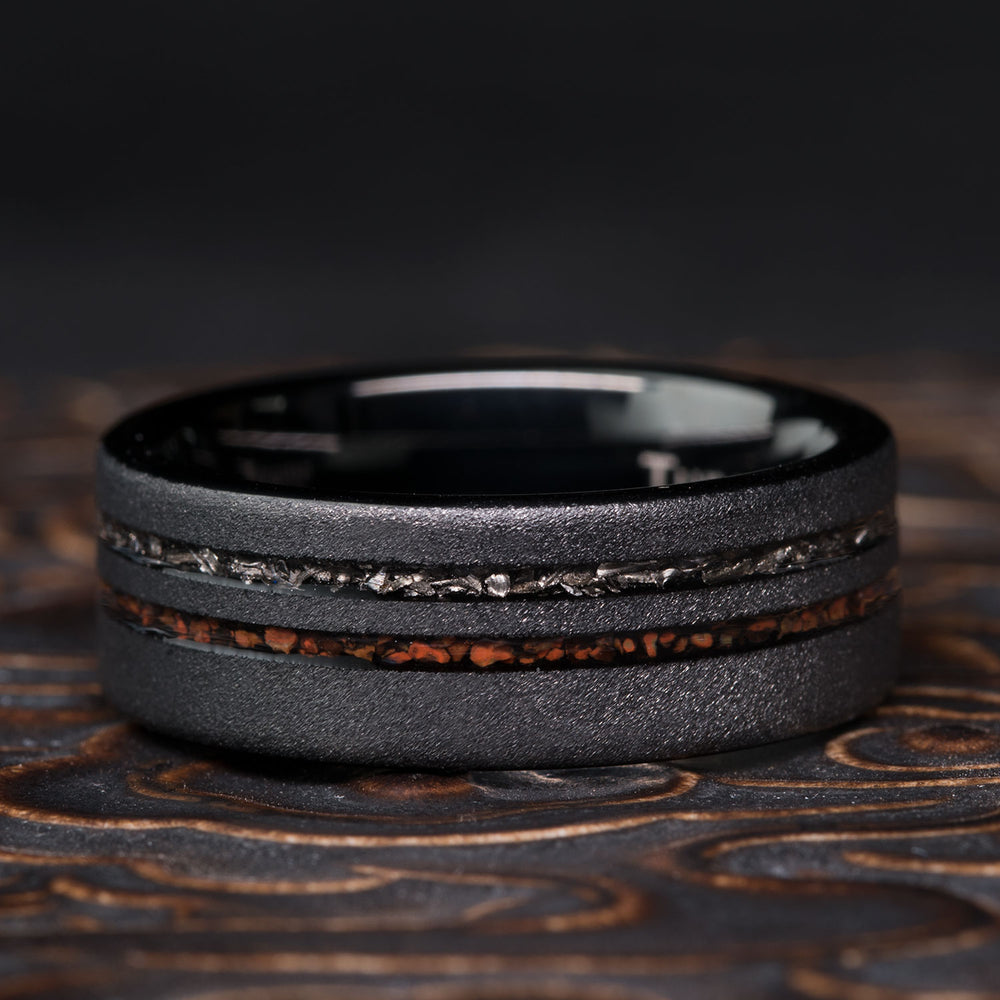 Black tungsten carbide wedding ring with inlaid dinosaur bone and meteorite fragments.