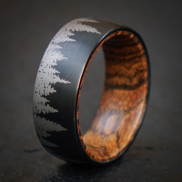 Black tungsten ring with laser-etched forest design and olive wood