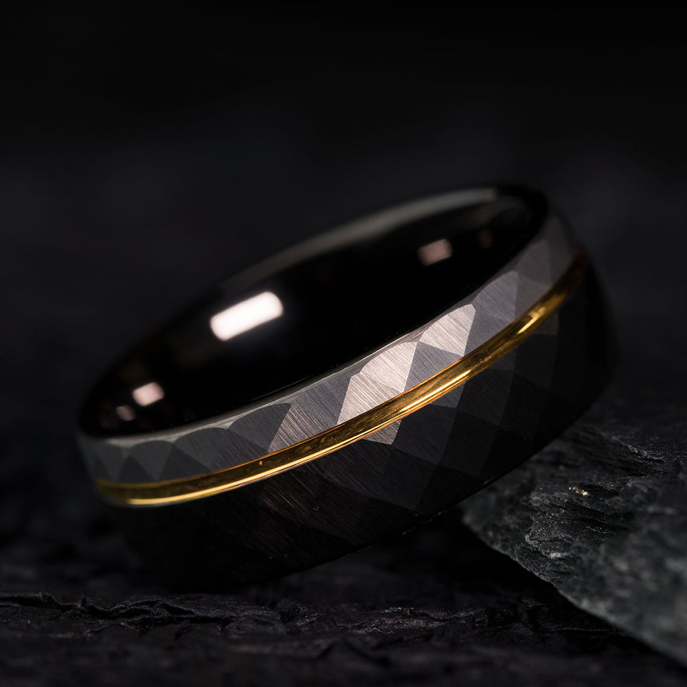 8mm hammered tungsten wedding band, black exterior, gold accent stripe, faceted pattern, product appearance.
