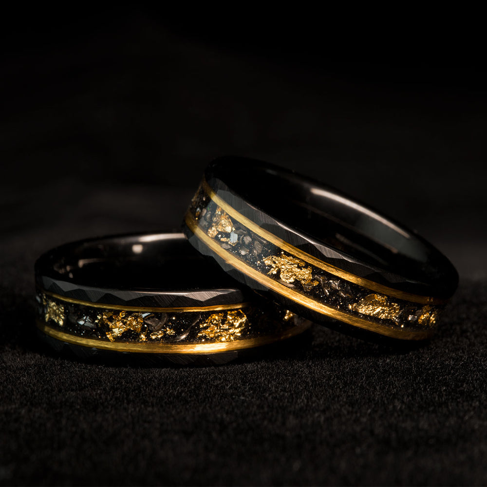 Two black tungsten rings with hammered finish, inlaid with Muonionalusta meteorite and 22k gold leaf accents.